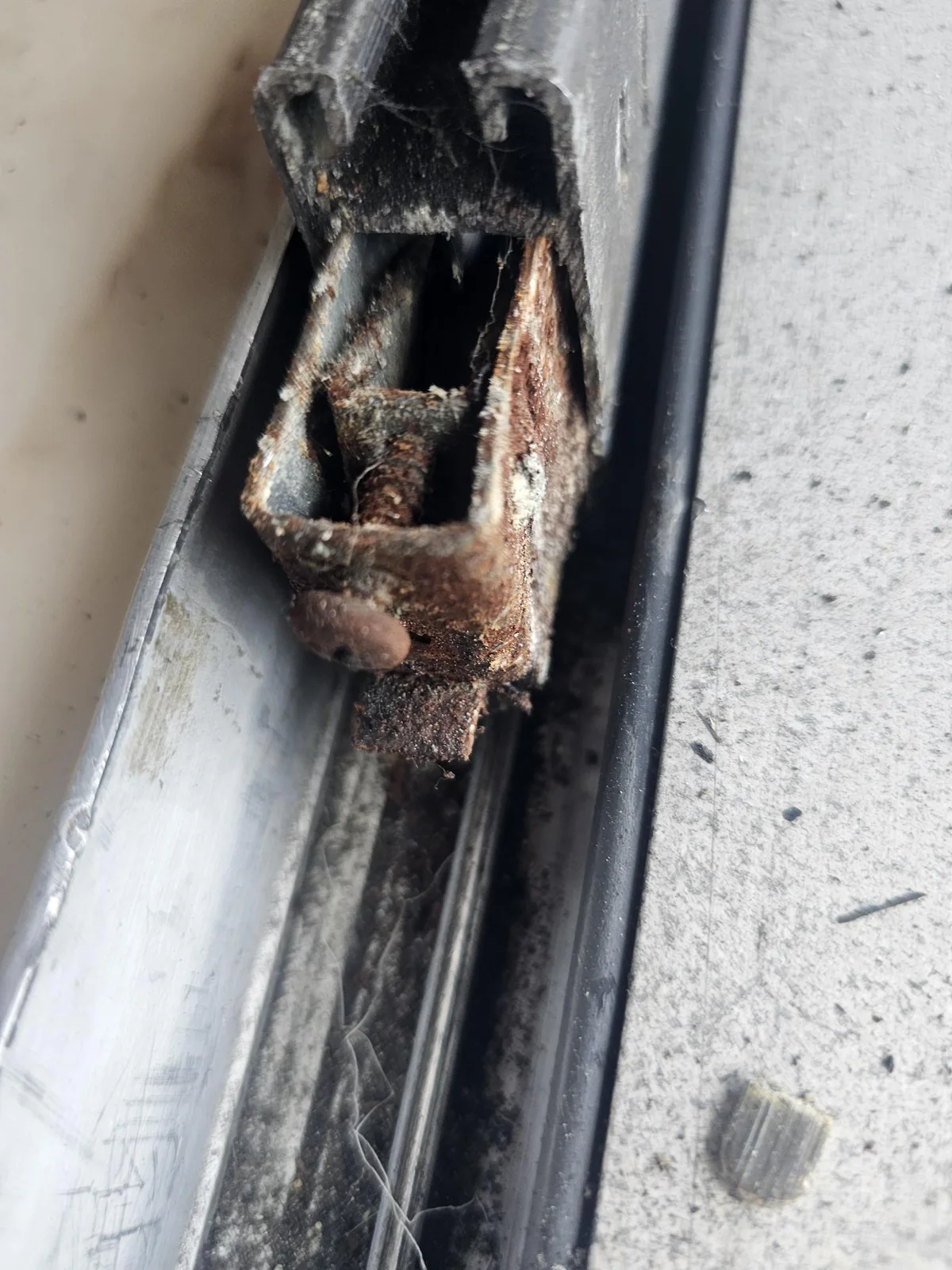 Corroded sliding door roller housing Corroded metal sliding door roller housing and adjustment screw beside the track