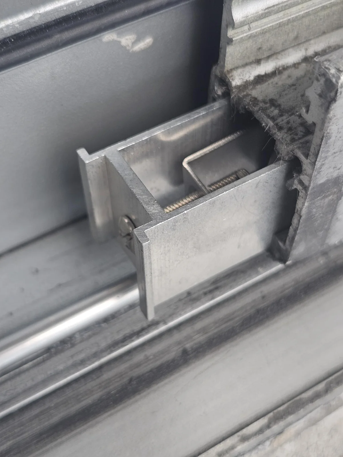 Sliding door roller housing detail Metal sliding door roller housing with an adjustment screw beside the bottom track